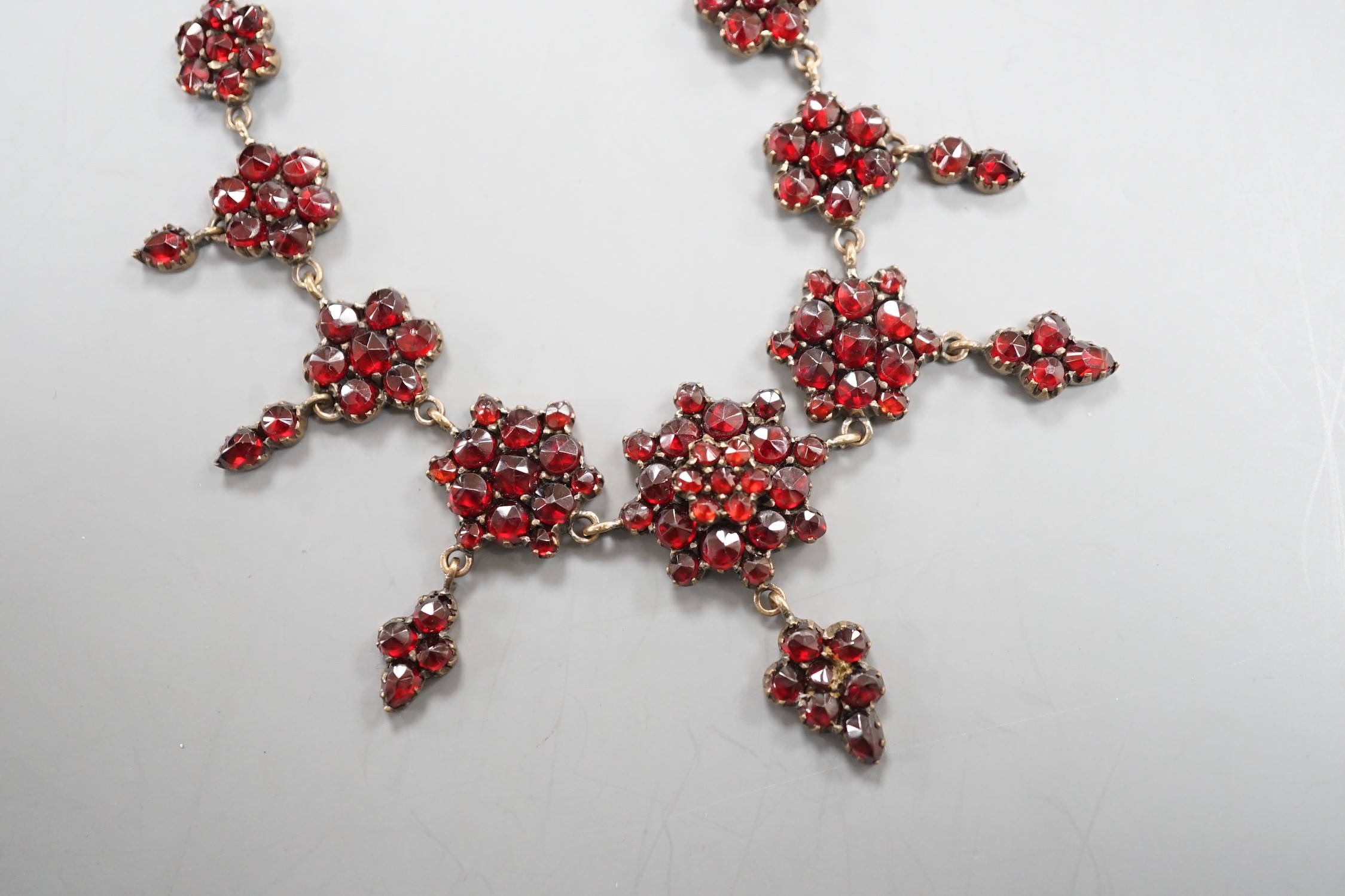 A late Victorian gilt and yellow metal, garnet cluster set drop necklace, 48cm.